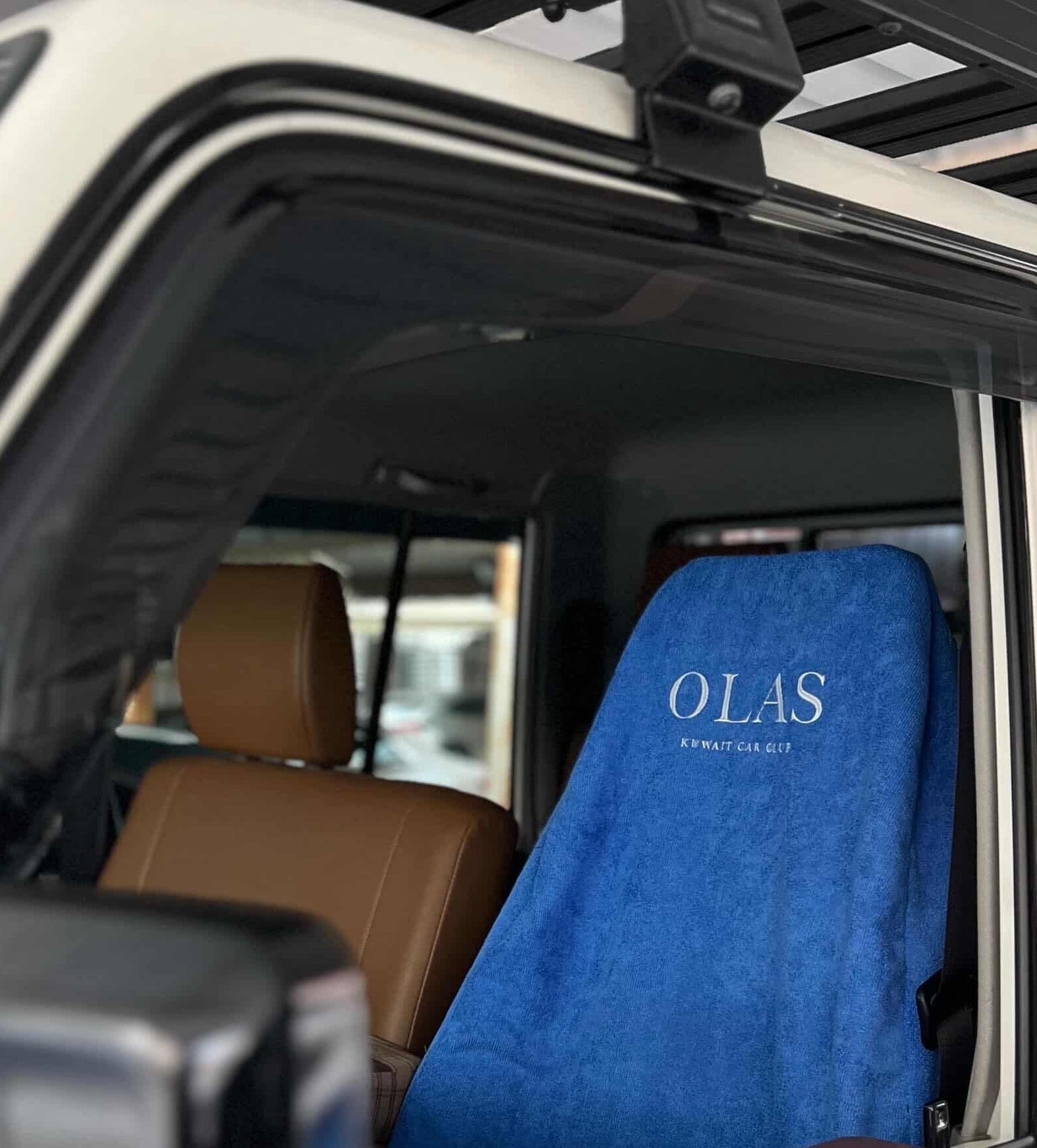 Car interior with a blue seat cover displaying 'OLAS' branding.
